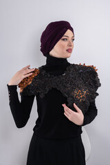 A stylish Muslim woman in a hijab presents her innovative handmade fashion accessory crafted from...