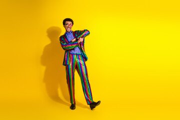 Young man wearing a colorful suit posing stylishly against a vibrant yellow background, expressing charisma
