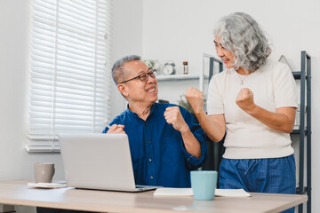 Obraz premium Happy Senior Couple Celebrating Success While Using Laptop at Home.