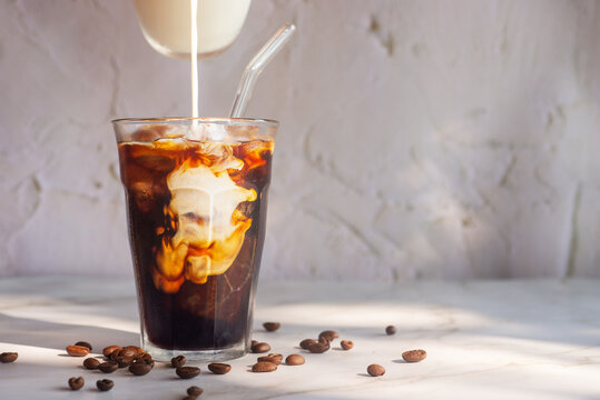pouring milk into a glass of homemade iced cold brew coffee, white cold brew. .