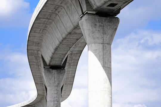 Low angle artistic photography of brutalist design concrete transportation infrastructure curve and pillars
