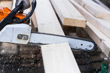 a chainsaw saws a wooden bar