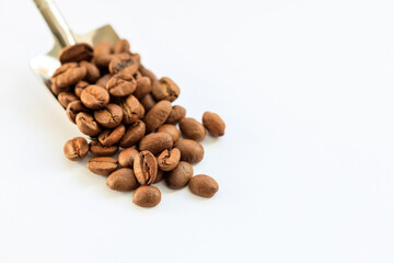 A spoonful of coffee beans is spread out on a white surface