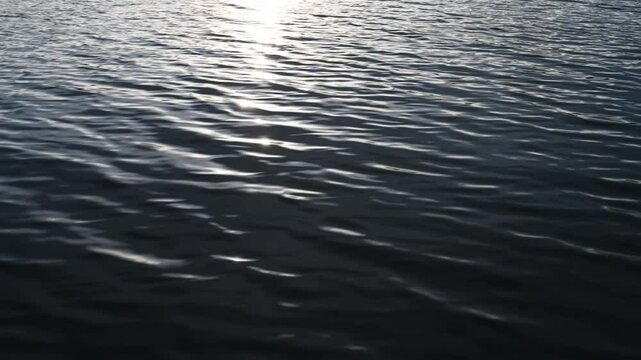 Isolated clos-up of small waves on a pond that is reflecting the early morning sun.
