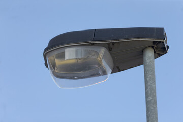 A street light featuring a transparent glass shade stands prominently against the backdrop of a...