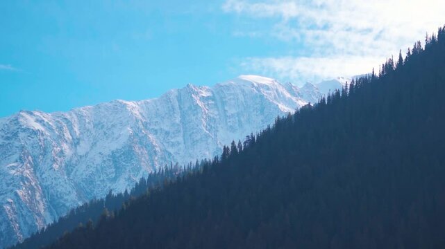 Clouds above the snowy Himalayan mountain peaks during a sunny day as seen from Triloknath village near Udaipur in Pattan Valley, Lahaul and Spiti district, Himachal Pradesh, India. Winter background.