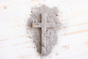 Ashes covered cross on a white wood background with copy space