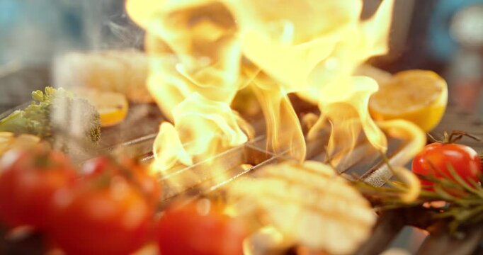Ultra slow-motion shot of salmon fish falling on flaming grill with other ingredients around it