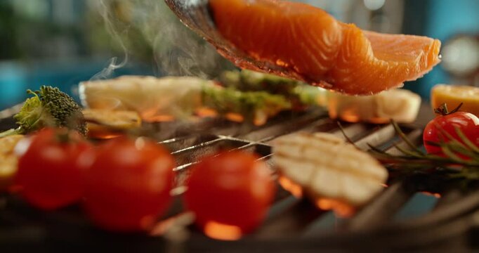 Slow-motion shot of a professional chef preparing sea food for launch, dropping salmon fish on fire grill with vegetables