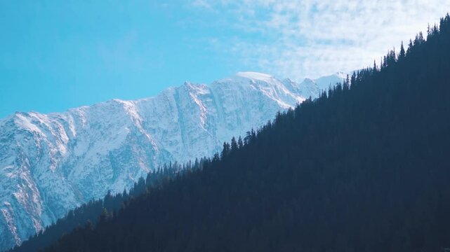 Clouds above the snowy Himalayan mountain peaks during a sunny day as seen from Triloknath village near Udaipur in Pattan Valley, Lahaul and Spiti district, Himachal Pradesh, India. Winter background.