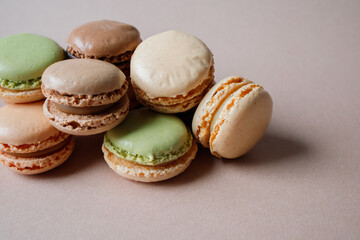 Multicolored macarons desserts with minimalistic beige background close up