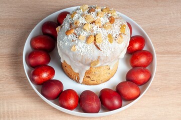 A delightful Easter cake adorned with nuts and coconut, encircled by vibrant red eggs on a white plate.