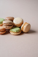 Multicolored macarons desserts with minimalistic beige background close up