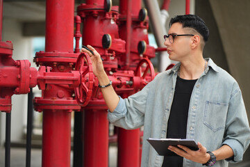 Male engineer inspects water pipelines in the engineering system area of the factory outside where...
