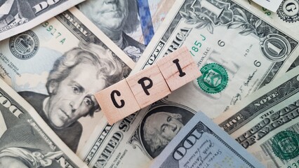 CPI acronym made of wooden letter cubes on pile of US dollar banknotes. Consumer Price Index