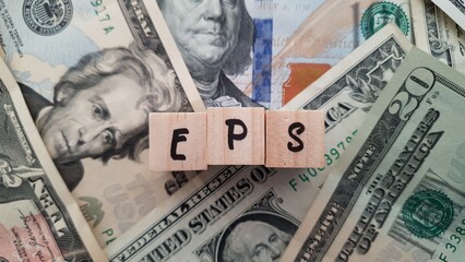 EPS acronym made of wooden letter cubes on pile of US dollar banknotes. Earnings Per Share