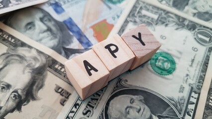 APY acronym made of wooden letter cubes on pile of US dollar banknotes. Annual Percentage Yield
