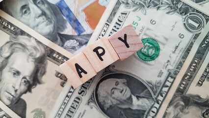 APY acronym made of wooden letter cubes on pile of US dollar banknotes. Annual Percentage Yield
