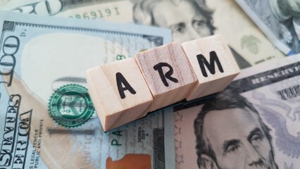 ARM acronym made of wooden letter cubes on pile of US dollar banknotes. Adjustable Rate Mortgage