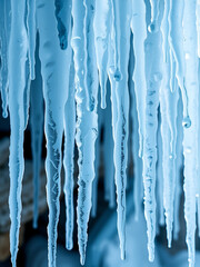 Group of light blue realistic icicles of different lengths connected at the top