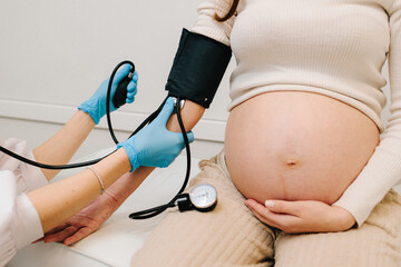 High pressure problem during pregnancy. Gynecologist measures blood pressure for pregnant patient...