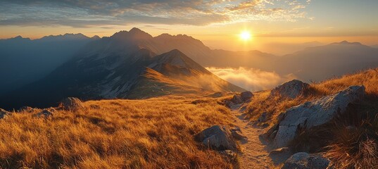 Golden hour light illuminating hiking path on mountain ridge in tatra mountains at sunrise, with panoramic view of mountains and clouds © oksa_studio