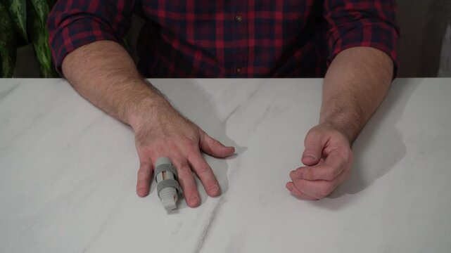 a man's hand with a plastic orthosis on the finger. a medical device used after an injury.