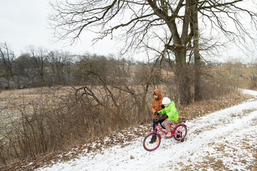 Joyful moments of a child riding a pink bike with adult guidance in a snowy landscape on a winter...