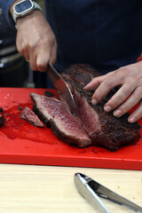 chef cortando filetes de secreto de cerdo ibérico en una tabla de corte con sus manos y un cuchillo