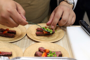 chef elaborando con sus manos y cuchara tapas y aperitivos de carne de solomillo con frutos rojos y verduras para degustar en un plato