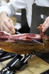 profesional del corte de jamón cortando con sus manos y u cuchillo especial de corte una paleta de jamón ibérico
