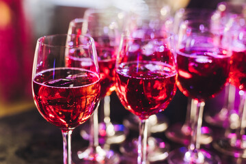 Alcohol setting on catering banquet table, row line of orange red coloured aperitif alcohol cocktails on party, negroni, spritz and others on bar counter, selection of liquor beverages on event