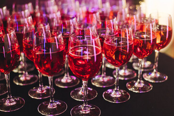 Alcohol setting on catering banquet table, row line of orange red coloured aperitif alcohol cocktails on party, negroni, spritz and others on bar counter, selection of liquor beverages on event