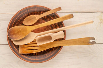 Wooden spoons and spatulas on a wooden table, close-up, top view.