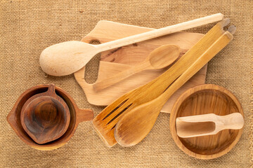 Wooden cups, spoons and spatulas on jute cloth, macro, top view.