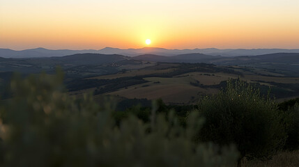 Obraz premium Golden sunset over rolling hills and valleys, seen through foreground foliage. Ideal for travel or nature themes