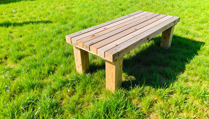 Fototapeta premium Wooden table on green grass under natural sunlight, outdoor relaxation