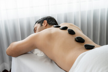 Hot stone massage at spa salon in luxury resort with day light serenity ambient, blissful man...