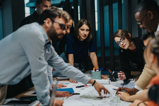 A diverse group of multigenerational business people collaborates on a project. They engage in innovative thinking and teamwork, highlighting creativity and cooperative strategies in a modern office - Powered by Adobe