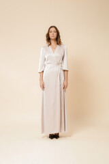 Serie of studio photos of female model in luxury minimalistic silk satin white maxi wrap dress.	