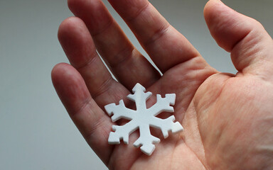 Premonition of an impending snowfall conceptual photo. Snowflake figurine on an elderly person's hand
