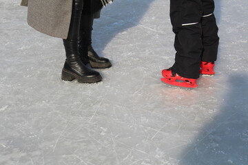 legs of a woman and child skating in winter