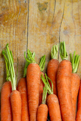 Aerial view of carrots with stem on wooden table, vertical with copy space