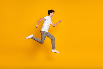 Fototapeta premium Young man in white t-shirt jumping with joy on vibrant yellow background, expressing happiness, energy, and a casual trendy style