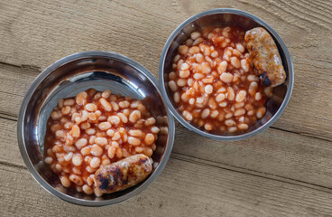 Beans in tomato sauce and grilled sausages on a metal plate.