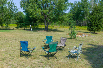 Five folding lawn chairs sitting out in a rural Michigan lawn.