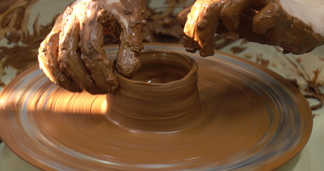 The potter's wheel. A close-up of the hands of a craftsman skillfully working with clay on a potter's wheel, giving it the shape of a clay product