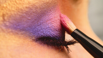 Make-up artist applies makeup to the upper eyelid, close-up.  Makeup artist applies a bright eye...