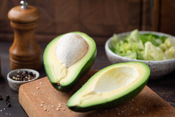 Avocado halves on wooden board closeup view. Healthy tropical fruit rich in fatty acids