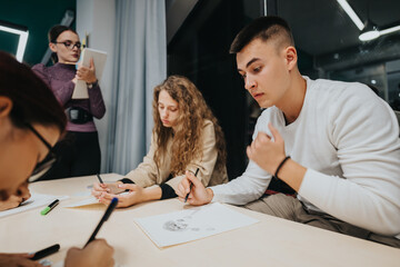 A group of students working together on creative projects in a classroom. A teacher observes and guides them, fostering a collaborative learning environment and teamwork skills.